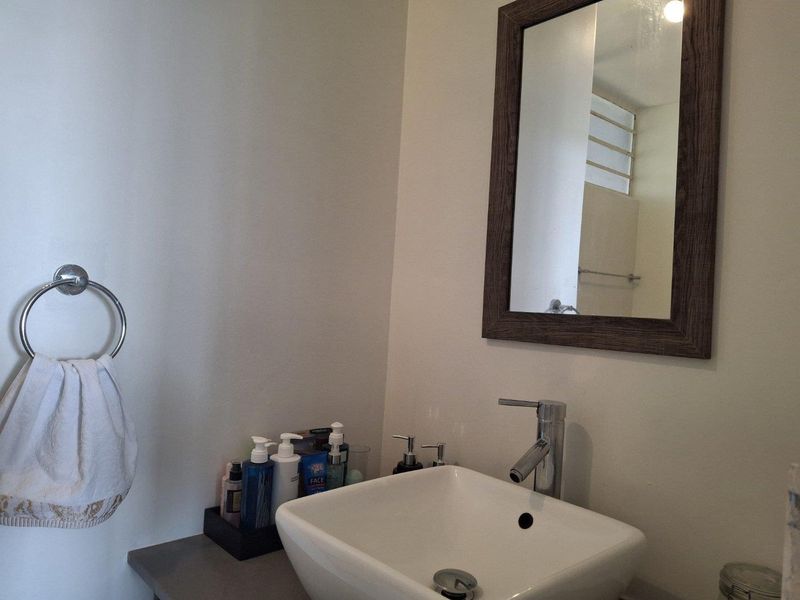 A functional bathroom vanity area featuring a modern vessel sink, chrome faucet, and a framed wall mirror.