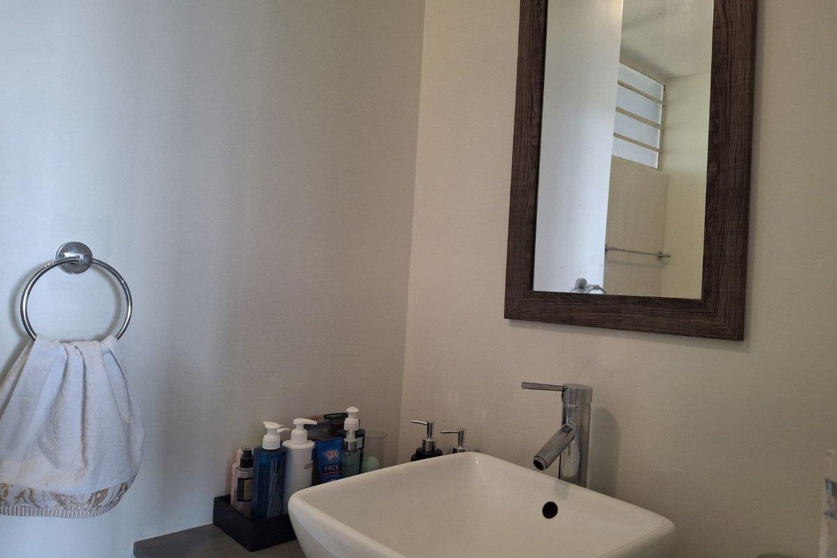 A functional bathroom vanity area featuring a modern vessel sink, chrome faucet, and a framed wall mirror.