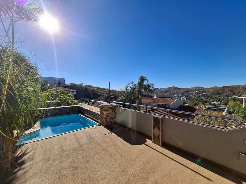 Elevated patio area featuring a small swimming pool, stone-clad accents, and modern balustrades with expansive hillside views.