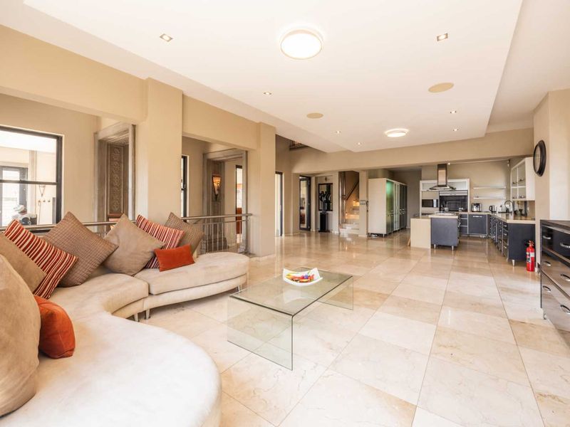 Spacious open-plan living area featuring large stone floor tiles, recessed lighting, and a modern kitchen with built-in cabinetry and a central island.