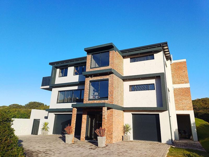 Modern three-story residential property featuring a combination of brick and rendered facade, double garage, and paved driveway.