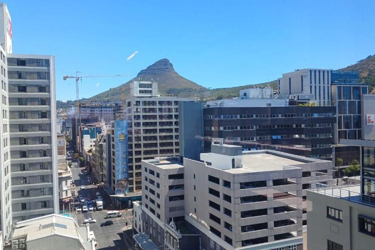 Elevated urban view overlooking city buildings and streets with a prominent mountain backdrop.