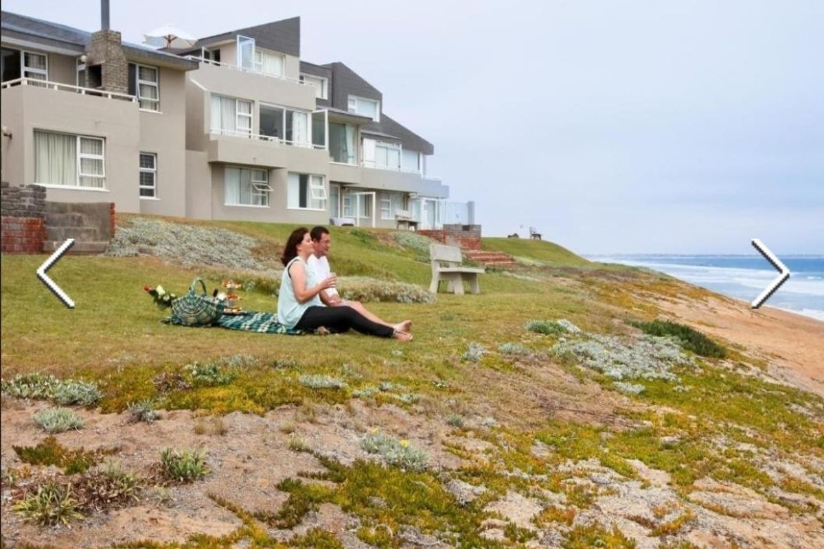 A view of the rear exterior facade of the townhouse complex, featuring landscaped coastal grounds and direct access to the beach.