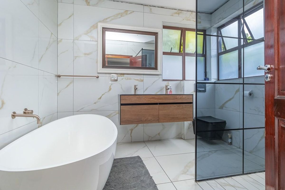 Modern bathroom featuring a freestanding bathtub, wall-mounted double vanity, and a glass-enclosed shower area with elegant marble-look wall tiles.