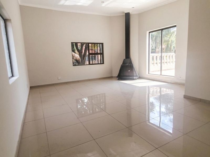 Spacious, light-filled living area featuring polished tile flooring, a modern freestanding fireplace, and large sliding doors leading to an outdoor space.