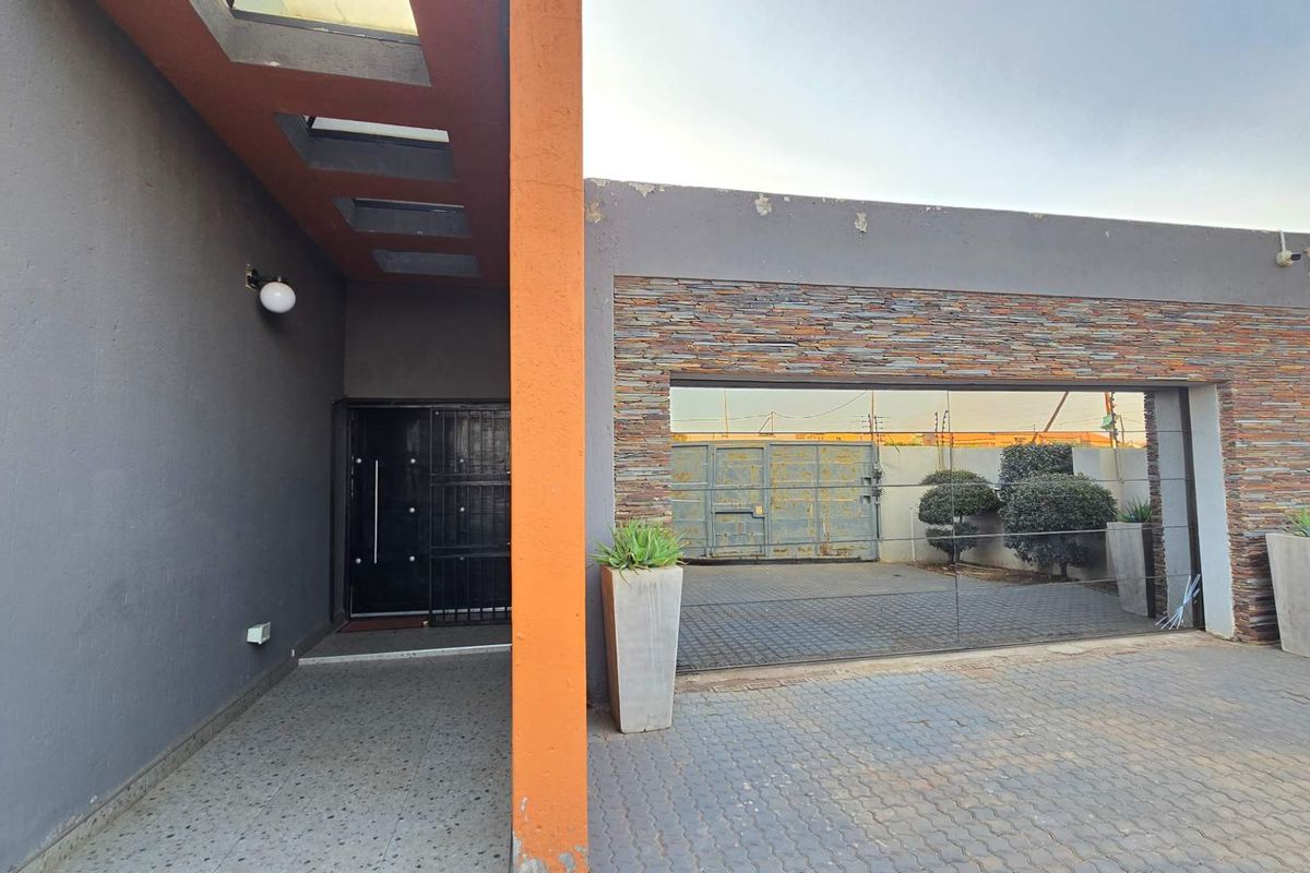 Front entrance area featuring stone cladding, paved driveway, and modern architectural details including integrated skylights and secure gated access.
