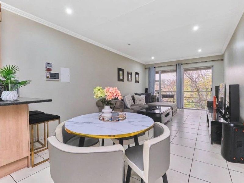 An open-plan living and dining area featuring tiled floors, recessed lighting, and a sliding door leading to a balcony.
