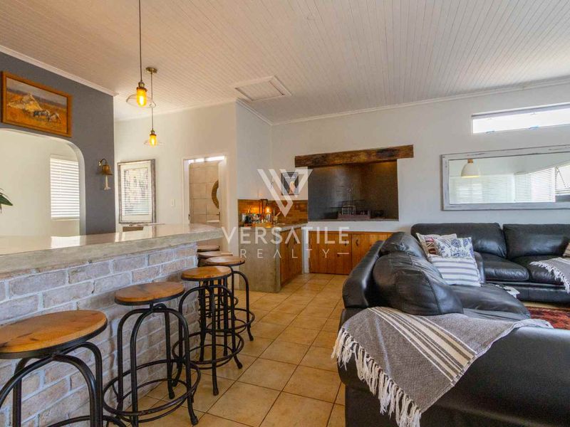 An open-plan living area featuring a brick breakfast bar, tiled flooring, and a beadboard ceiling, creating a warm and inviting space.