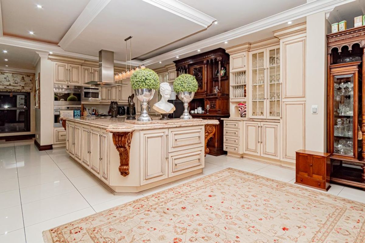 Spacious kitchen featuring custom cabinetry, a large central island with stone countertops, integrated appliances, and recessed ceiling lighting with decorative molding.