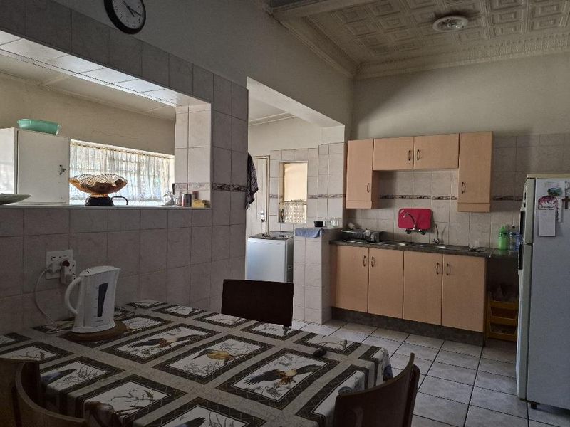 Open plan kitchen and dining area featuring tiled flooring, built-in cabinetry, a double sink, and a decorative pressed metal ceiling.