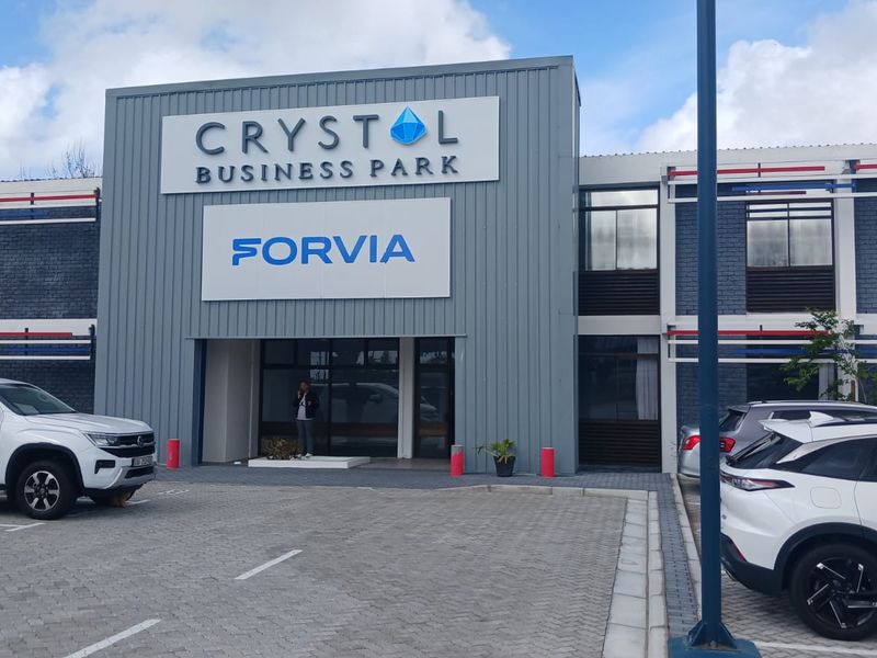 Front exterior view of the Crystol Business Park office building, featuring modern metal cladding, prominent signage, and a paved parking area.