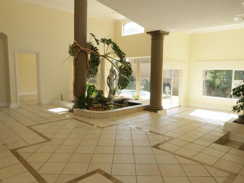 Spacious open-plan living area featuring decorative columns, tiled flooring with inlay detail, a sunken floor section, and an integrated indoor planter.