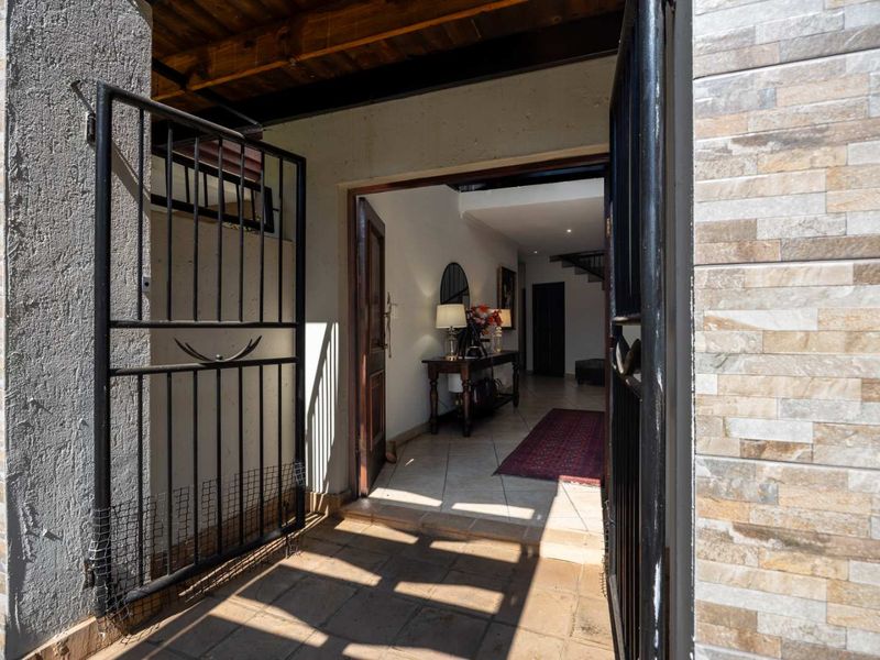 A welcoming entrance area featuring a secure metal gate, stone-clad exterior walls, and a view into the interior hallway with tiled flooring.