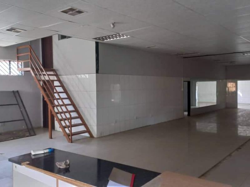 Spacious open-plan industrial unit featuring tiled flooring, a metal staircase, and suspended ceiling with integrated lighting, suitable for various commercial or industrial uses.