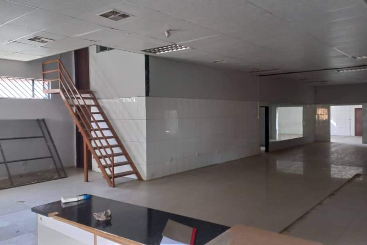 Spacious open-plan industrial unit featuring tiled flooring, a metal staircase, and suspended ceiling with integrated lighting, suitable for various commercial or industrial uses.