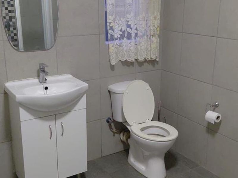 A functional bathroom featuring full-height wall tiling, a modern vanity unit with basin, and a standard toilet suite.