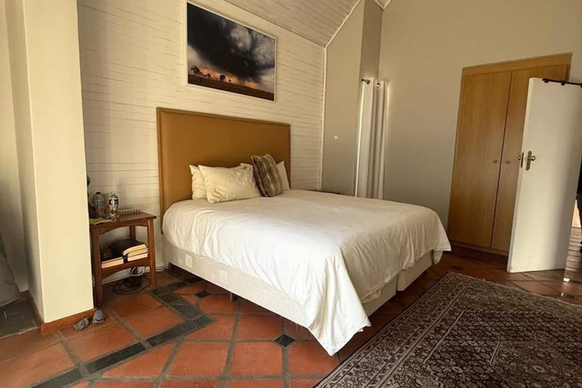 A bedroom featuring vaulted timber-paneled ceilings, terracotta tiled flooring with decorative inlays, and built-in wooden cabinetry.