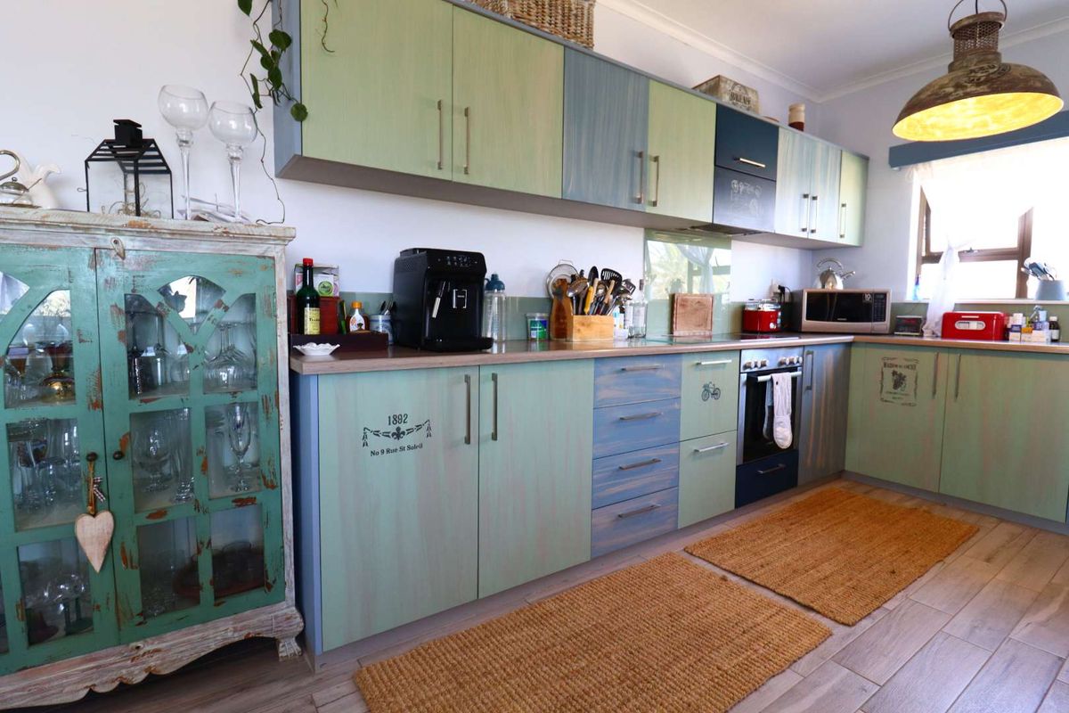 A kitchen featuring custom-painted cabinetry, integrated oven, and hob, with wood-look flooring and ample counter space.