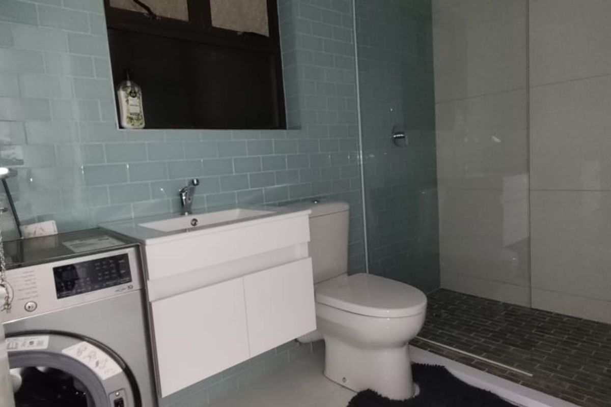 Modern bathroom featuring a vanity with basin, toilet, and a walk-in shower with glass screen and stylish subway wall tiling.