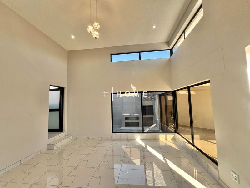 Spacious, modern living area featuring high ceilings, large windows, and polished porcelain tile flooring with direct access to an outdoor patio area.