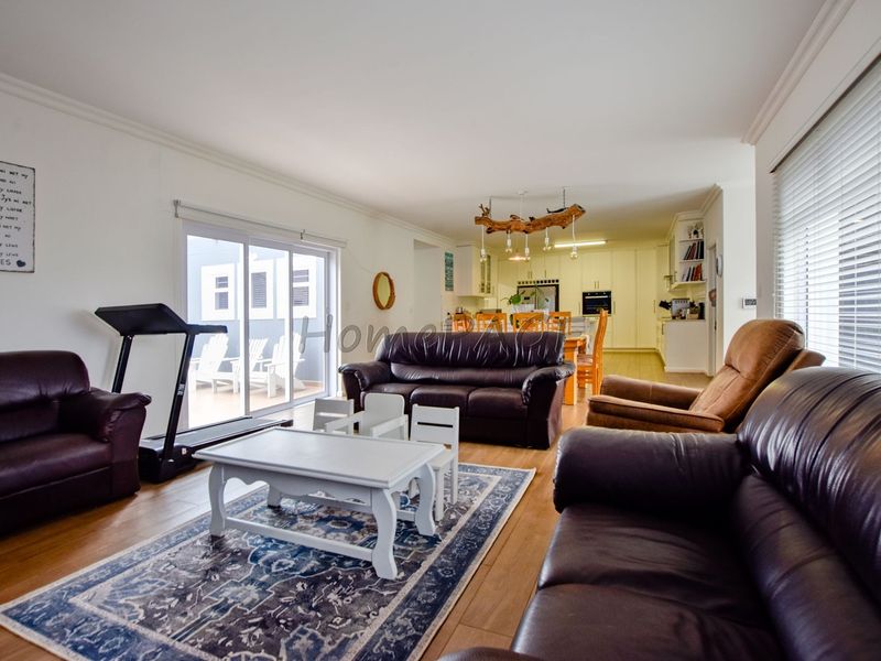 Spacious open-plan living and dining area featuring laminate flooring, sliding doors to the patio, and a well-appointed kitchen with built-in cabinetry and appliances.