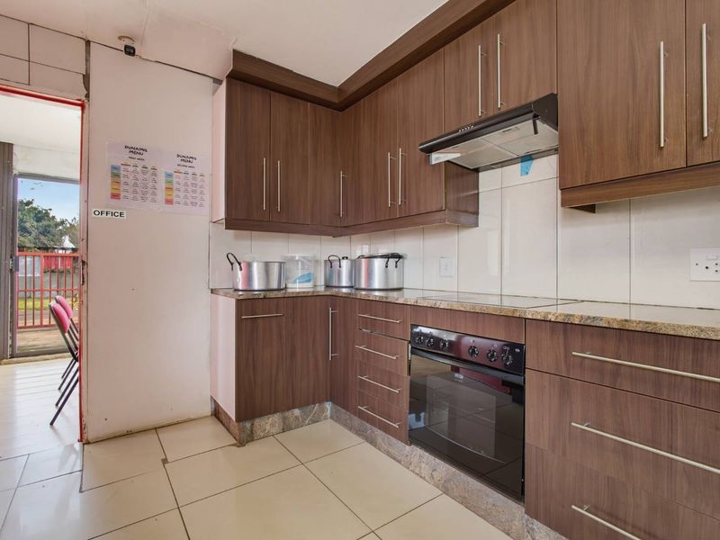 A functional kitchen featuring wood-finish cabinetry, granite countertops, and built-in cooking appliances, with direct access to an outdoor area.