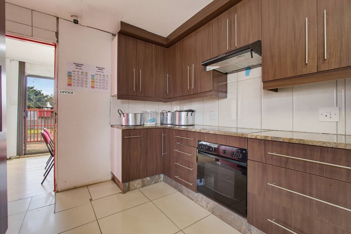 A functional kitchen featuring wood-finish cabinetry, granite countertops, and built-in cooking appliances, with direct access to an outdoor area.