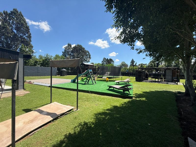 Spacious backyard featuring a manicured lawn, artificial turf play area, and a covered outdoor entertainment structure.
