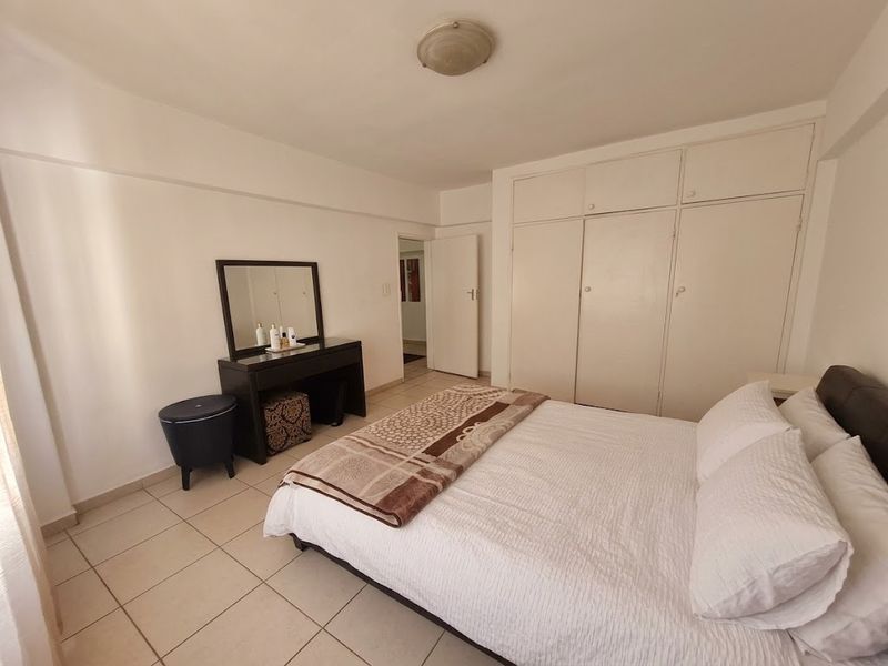A bedroom featuring tiled flooring and built-in cupboards, offering a functional space with potential for cosmetic updates to enhance its appeal.