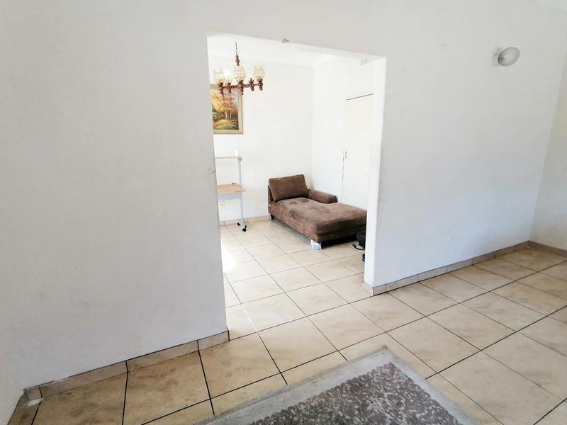 A living area featuring ceramic tiled flooring and a neutral wall finish, providing a functional space with potential for modernization.