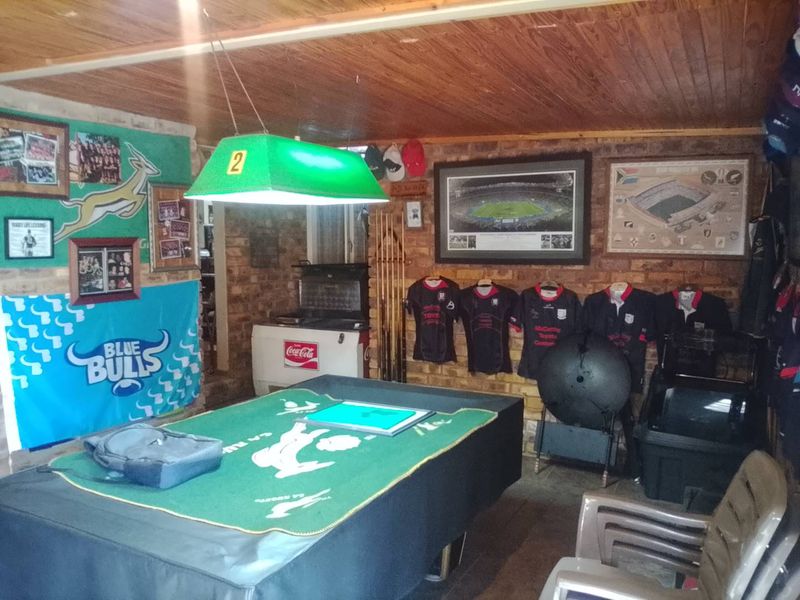 A casual entertainment room featuring exposed brick walls and a timber ceiling, currently set up as a recreational space.