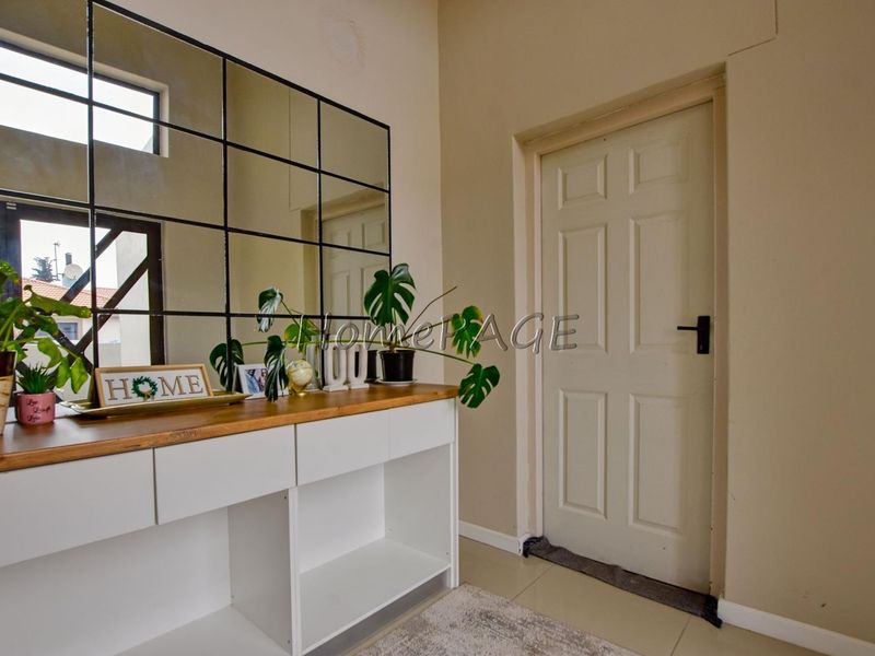 An entry area featuring a grid-style wall mirror, a built-in white console cabinet with a wooden top, and a classic panelled door.