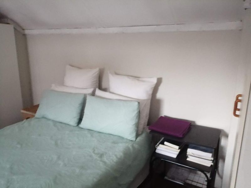 A compact bedroom featuring a sloped ceiling and neutral wall finishes, providing a cozy and functional sleeping space.