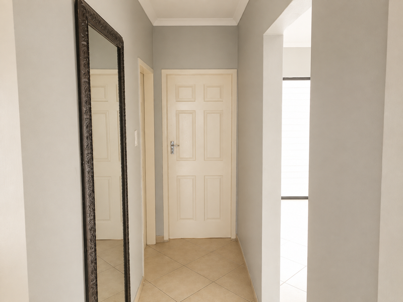 A clean and well-maintained hallway featuring neutral wall tones, tiled flooring, and a classic panelled interior door.