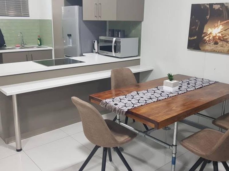 An open-plan kitchen and dining area featuring modern cabinetry, a breakfast bar island with a built-in hob, and tiled flooring throughout.