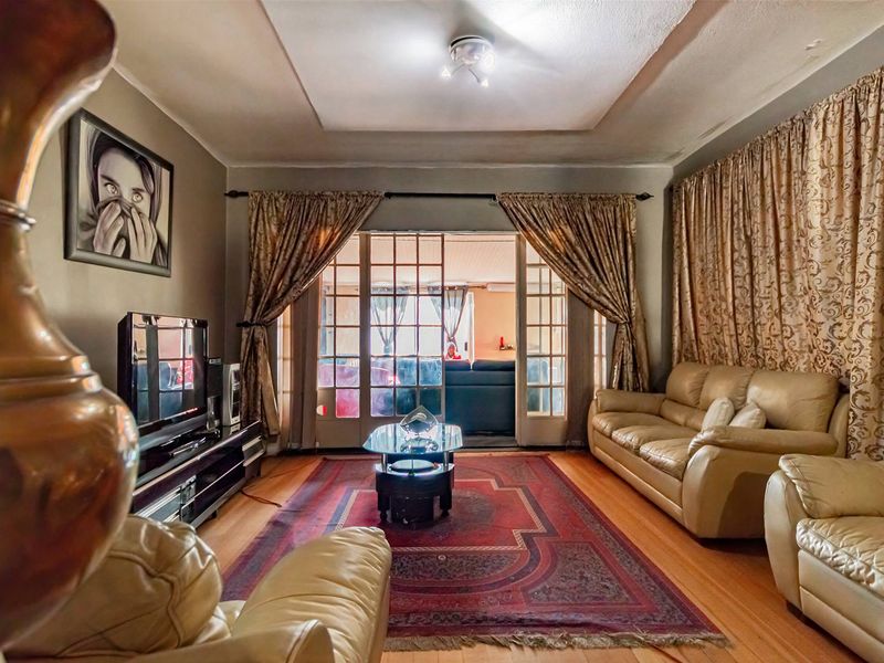 A living room featuring hardwood flooring, a recessed ceiling detail, and glass-paned french doors leading to an adjacent space.