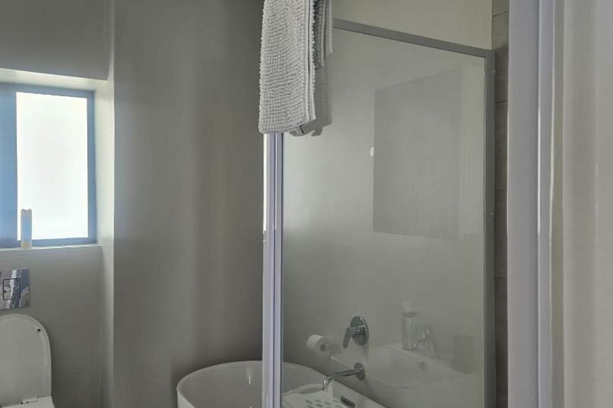 Modern bathroom featuring a freestanding bathtub, separate shower enclosure, and tiled flooring in a clean, neutral aesthetic.