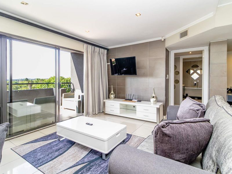 Modern living room featuring tiled flooring, recessed lighting, and large sliding glass doors opening onto a private balcony.
