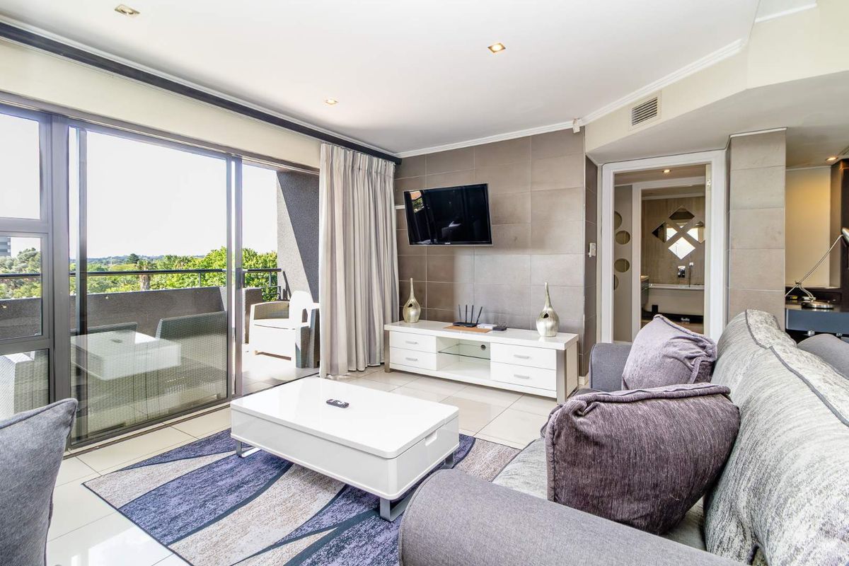 Modern living room featuring tiled flooring, recessed lighting, and large sliding glass doors opening onto a private balcony.