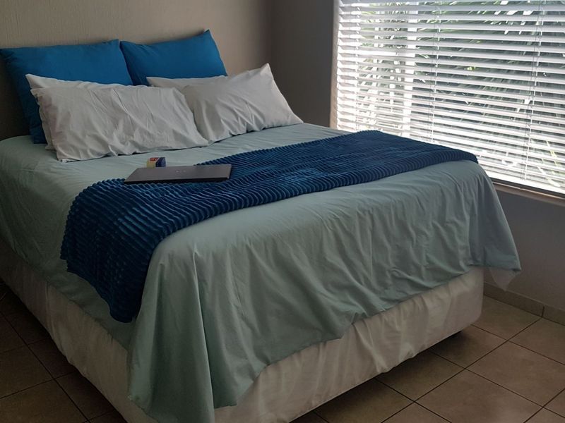 A bedroom featuring tiled flooring and venetian blinds, providing a functional space with natural light.