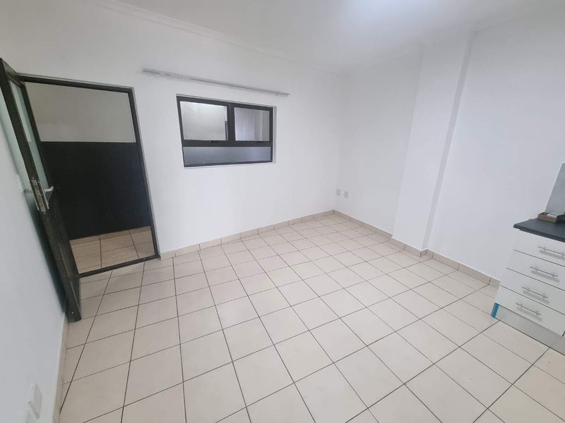 A compact, empty kitchen area featuring tiled flooring, white walls, and basic built-in cabinetry, offering a clean slate for potential updates.