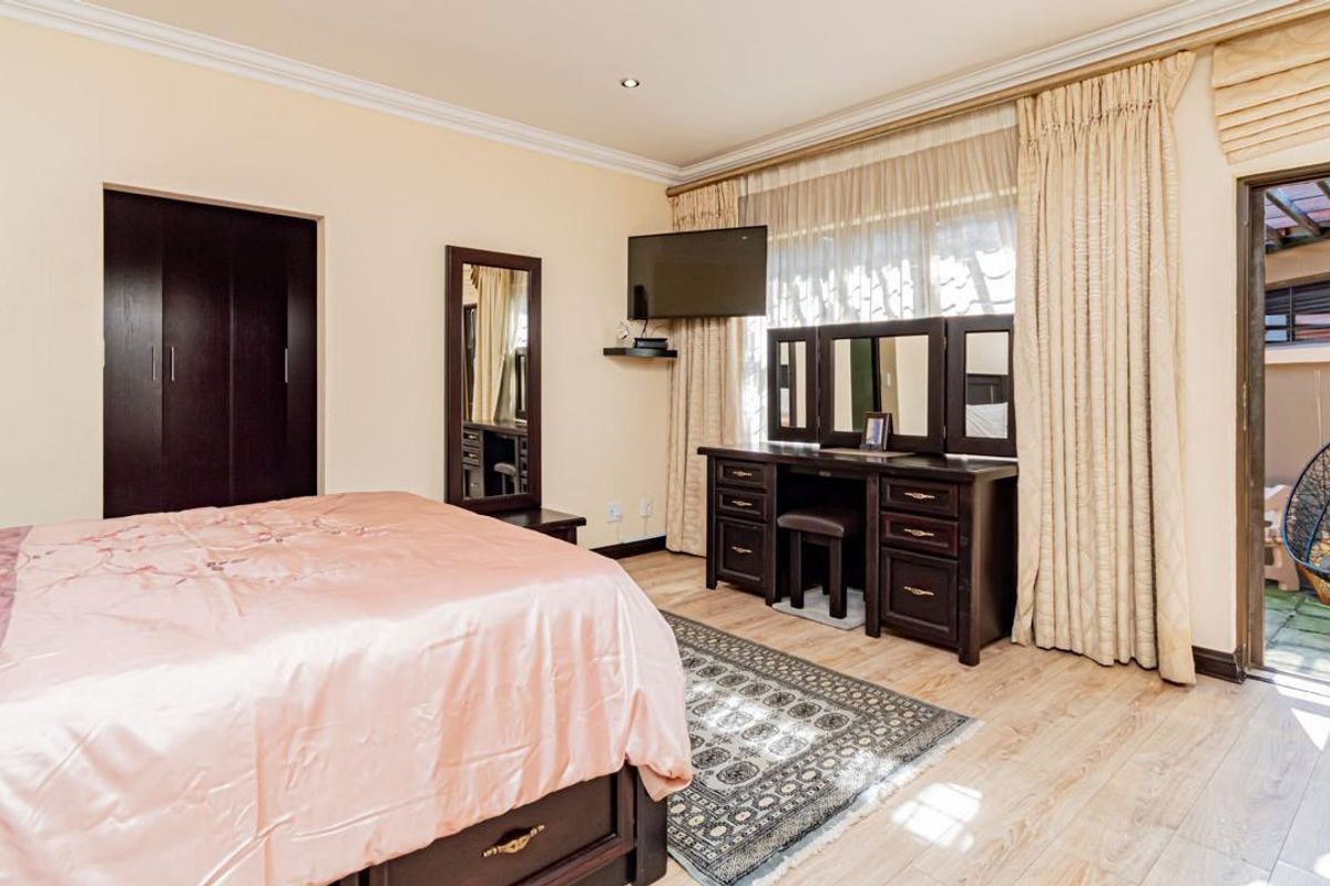 Spacious bedroom featuring laminate flooring, built-in cupboards, and direct access to an outdoor patio area through a sliding door.