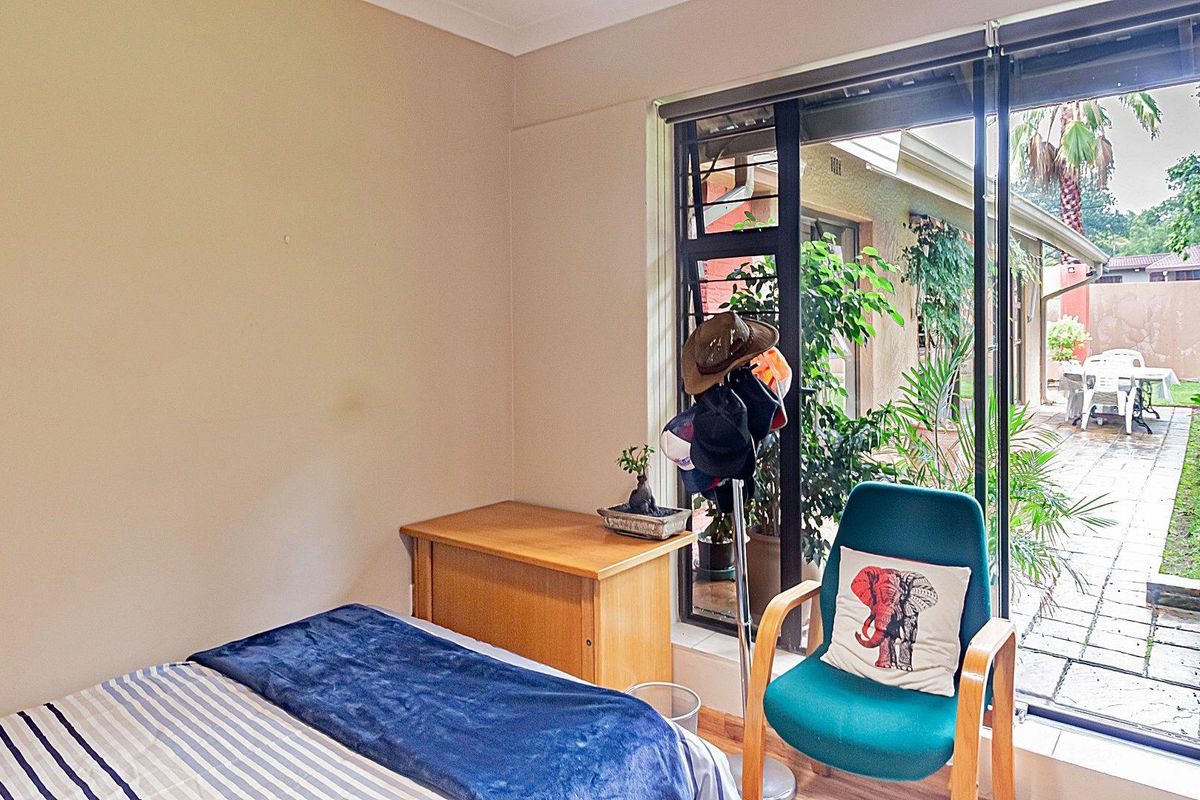 A bedroom featuring large sliding glass doors that provide direct access to a paved patio and garden area.