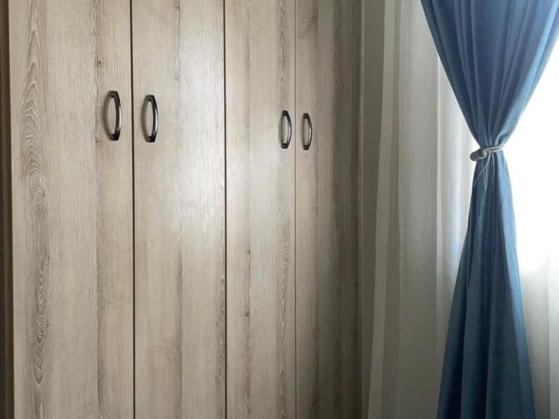 A bedroom featuring modern wood-grain built-in cupboards with dark hardware.