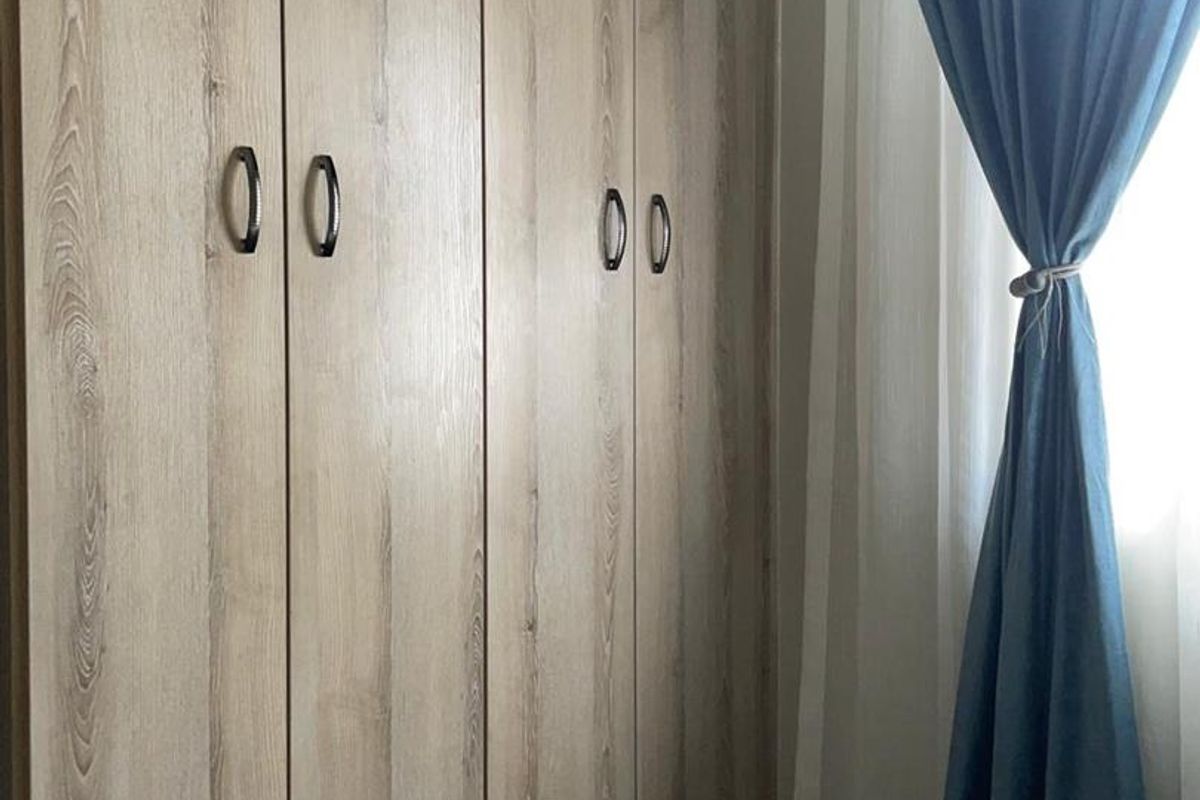 A bedroom featuring modern wood-grain built-in cupboards with dark hardware.