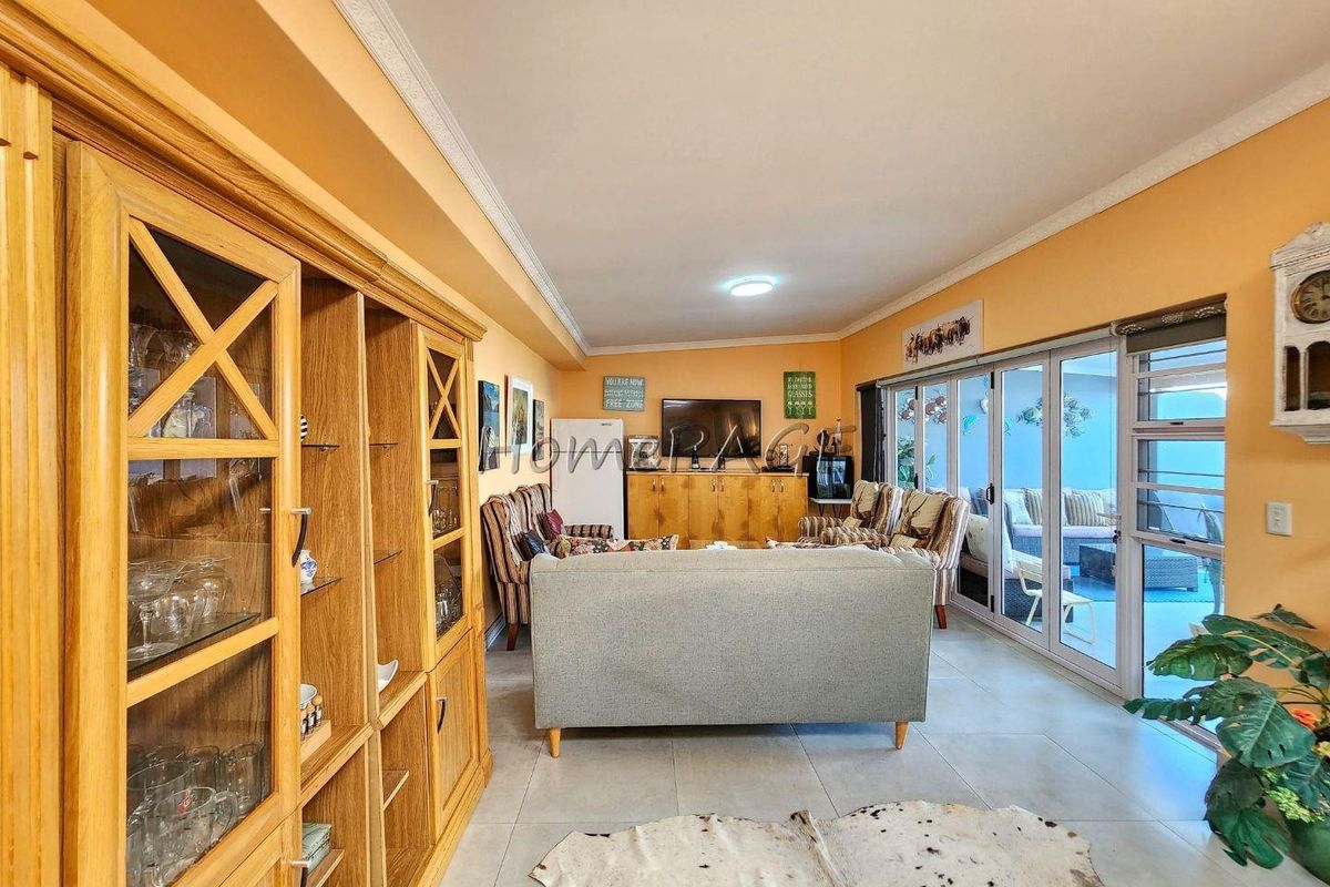 Spacious living room featuring tiled flooring, crown molding, and large sliding glass doors that provide seamless access to the outdoor patio area.