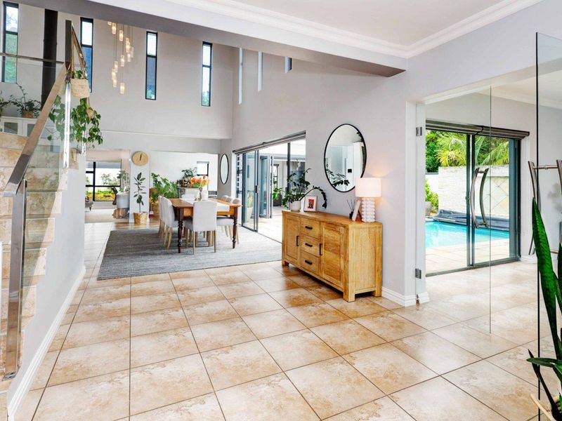 Spacious open-plan living area featuring high ceilings, tiled flooring, and seamless indoor-outdoor flow to the pool area through large sliding glass doors.