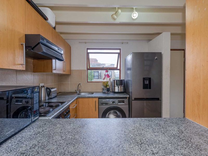 Functional kitchen featuring laminate cabinetry, granite countertops, tiled backsplash, and exposed ceiling beams, providing a practical workspace with integrated appliances.