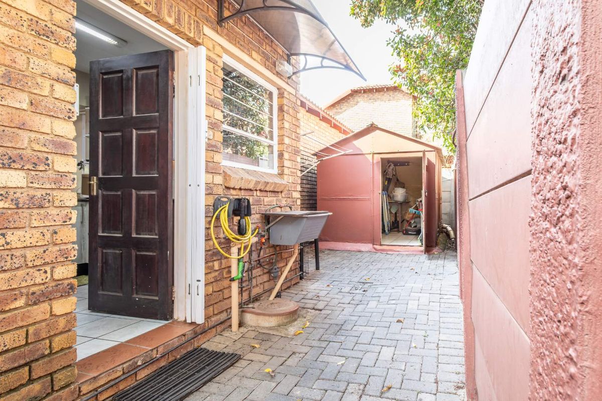 A paved rear courtyard area featuring a utility sink, an external storage shed, and direct access to the interior.