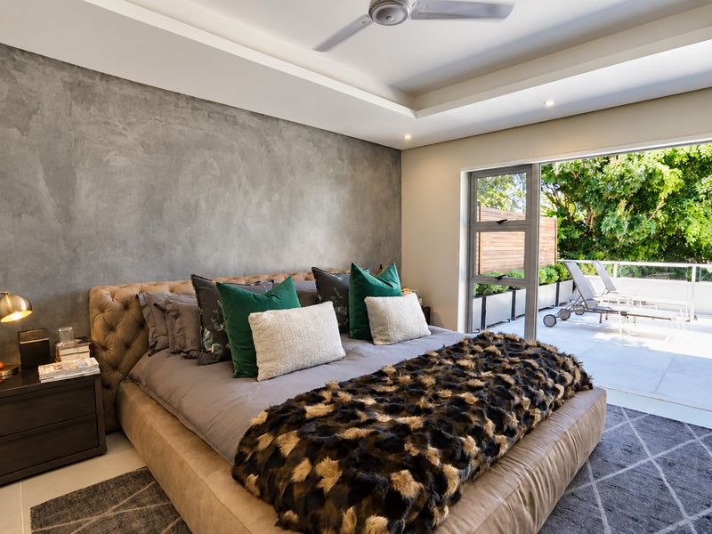 Spacious bedroom featuring a textured feature wall, recessed ceiling with fan, and large sliding glass doors opening onto a private balcony.